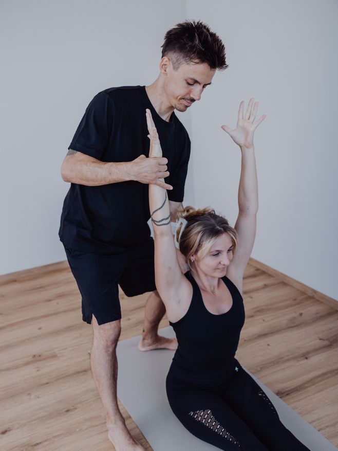 Trainer unterstützt eine Teilnehmerin im Kurs Vitality Yoga